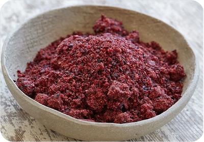 Red Tart Cherry Powder in a stone bowl on a wooden surface. Tart Cherry Powder contains melatonin, which regulates sleep, and anthocyanins, which reduce oxidative stress and inflammation in the brain.